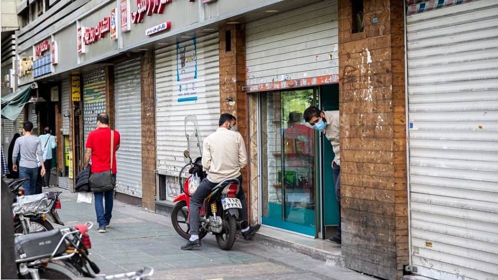 An Iranian man peers inside a partially closed shop