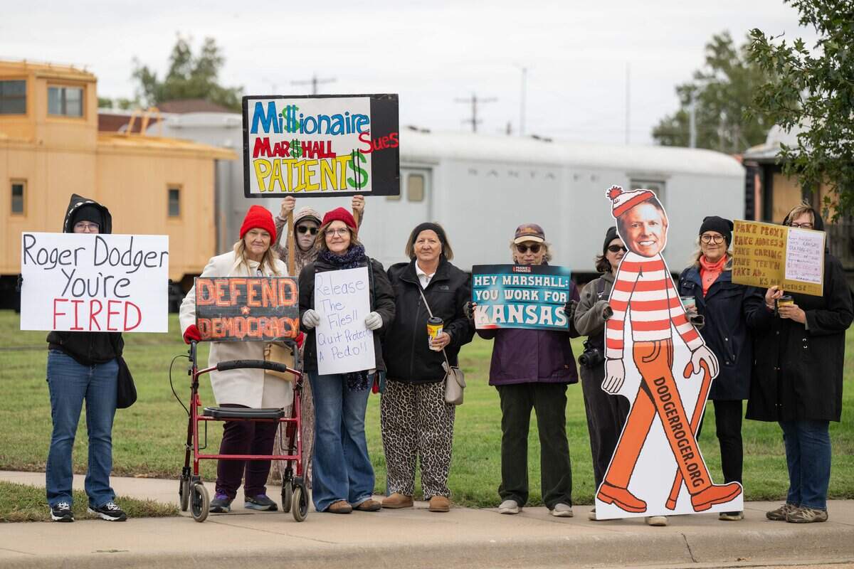 Protesters hold signs in opposition to U.S. Sen. Roger Marshall (R-Kansas) outside a legislative breakfast at Grand Overland Station, on Friday, Oct. 16, 2026, in Topeka. Marshall, who rarely makes scheduled appearances, is facing a reelection challenge from Rev. Adam Hamilton, a Johnson County megachurch pastor.
