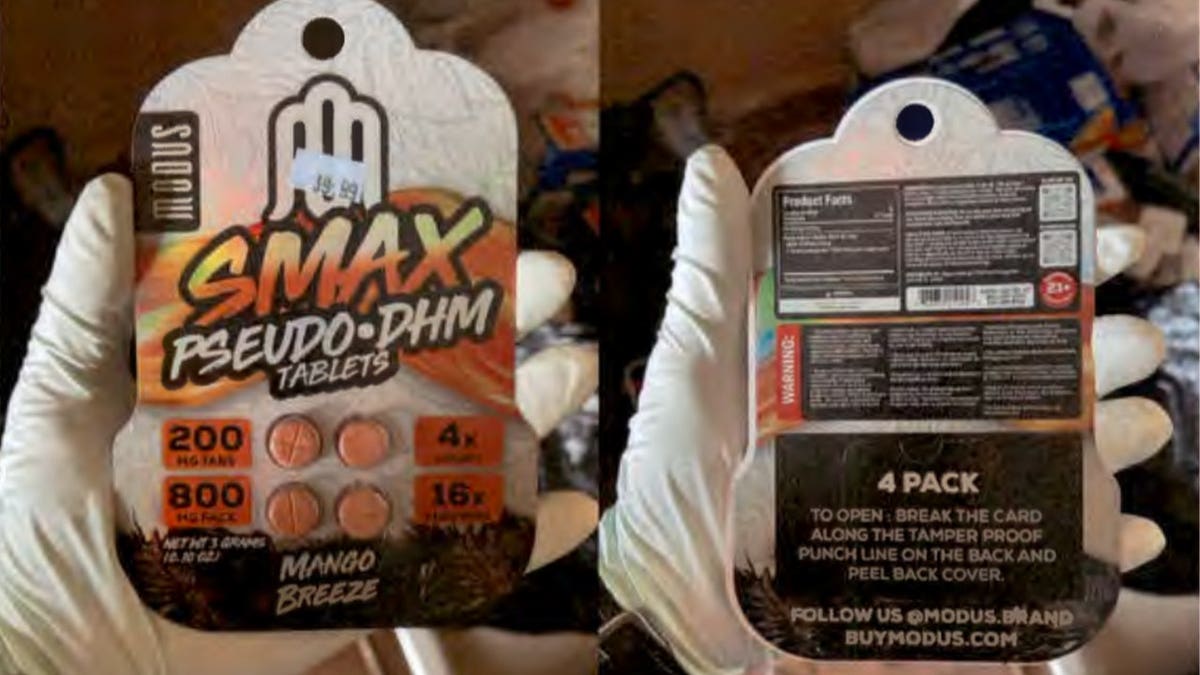 A gloved hand holds the front and back of a "Smax Pseudo-DHM" tablet package in the Mango Breeze flavor, showing four orange tablets and product labeling.