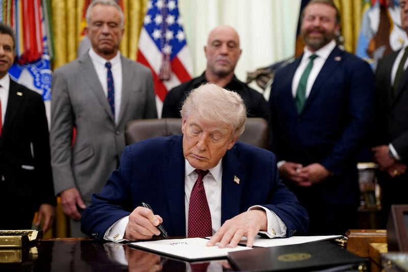 FILE PHOTO: FILE PHOTO: U.S. President Donald Trump signs an executive order encouraging more research into ibogaine, next to U.S. Health and Human Services (HHS) Secretary Robert F. Kennedy Jr., Joe Rogan, and Americans for Ibogaine CEO W. Bryan Hubbard, in the Oval Office of the White House in Washington, D.C., April 18, 2026. REUTERS/Nathan Howard/File Photo/File Photo