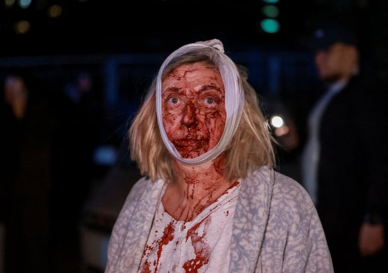 SENSITIVE MATERIAL. THIS IMAGE MAY OFFEND OR DISTURB A wounded woman stands at the site of an apartment building damaged during a Russian missile strike, amid Russia's attack on Ukraine, in Kyiv October 13, 2026. REUTERS/Yan Dobronosov