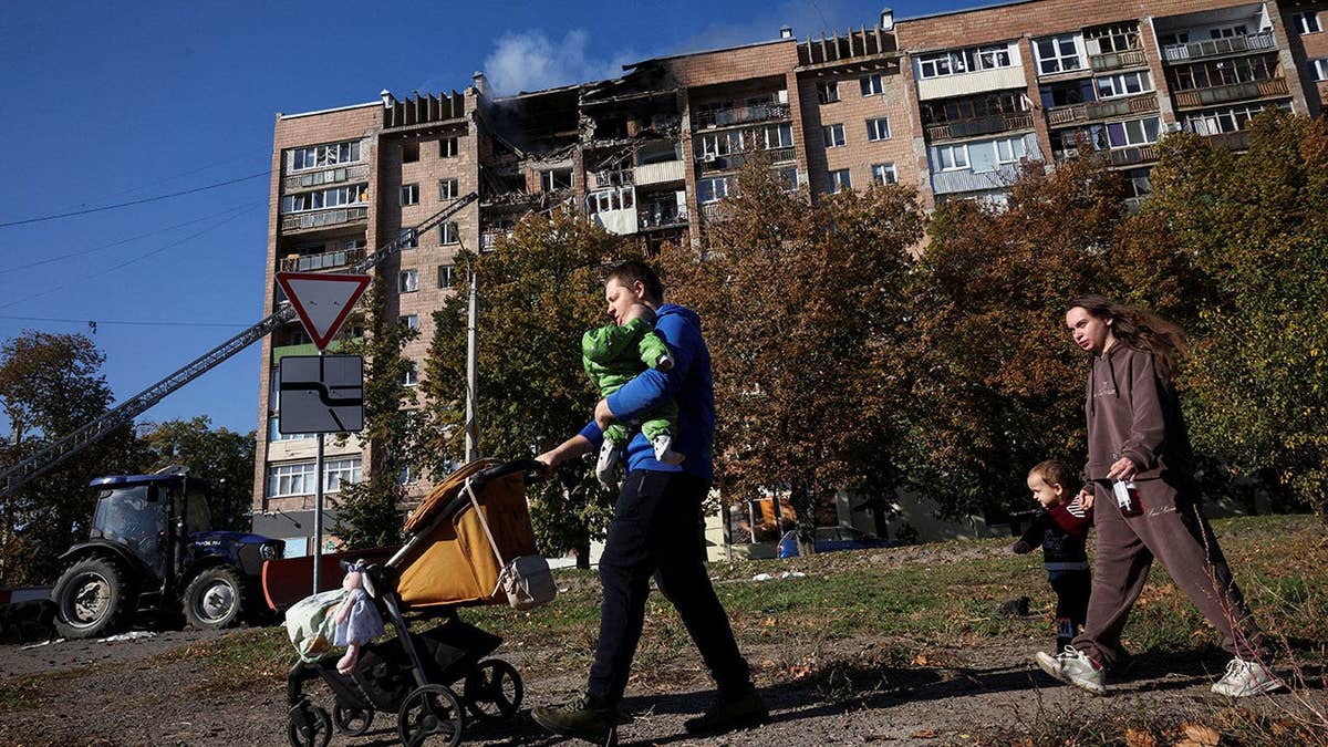 A family walks past an apartment building that was hit by a Russian drone, amid Russia's attack on Ukraine