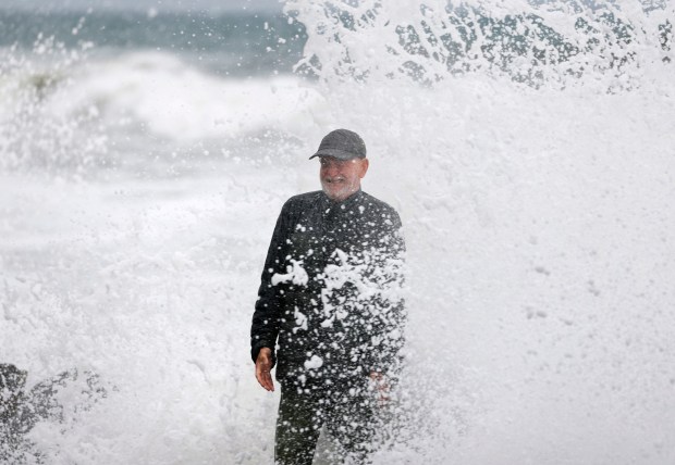 Oceanside, CA - October 11: Phillip Soufer stands on The Strand while waves break during a high tide as the remnants of Tropical Storm Rachel moved through the region on October 11, 2026 in Oceanside, CA. (K.C. Alfred / The San Diego Union-Tribune)