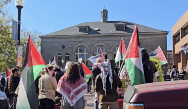 Demonstrators carrying Palestinian flags gather outside a stone building at Seattle Central College.