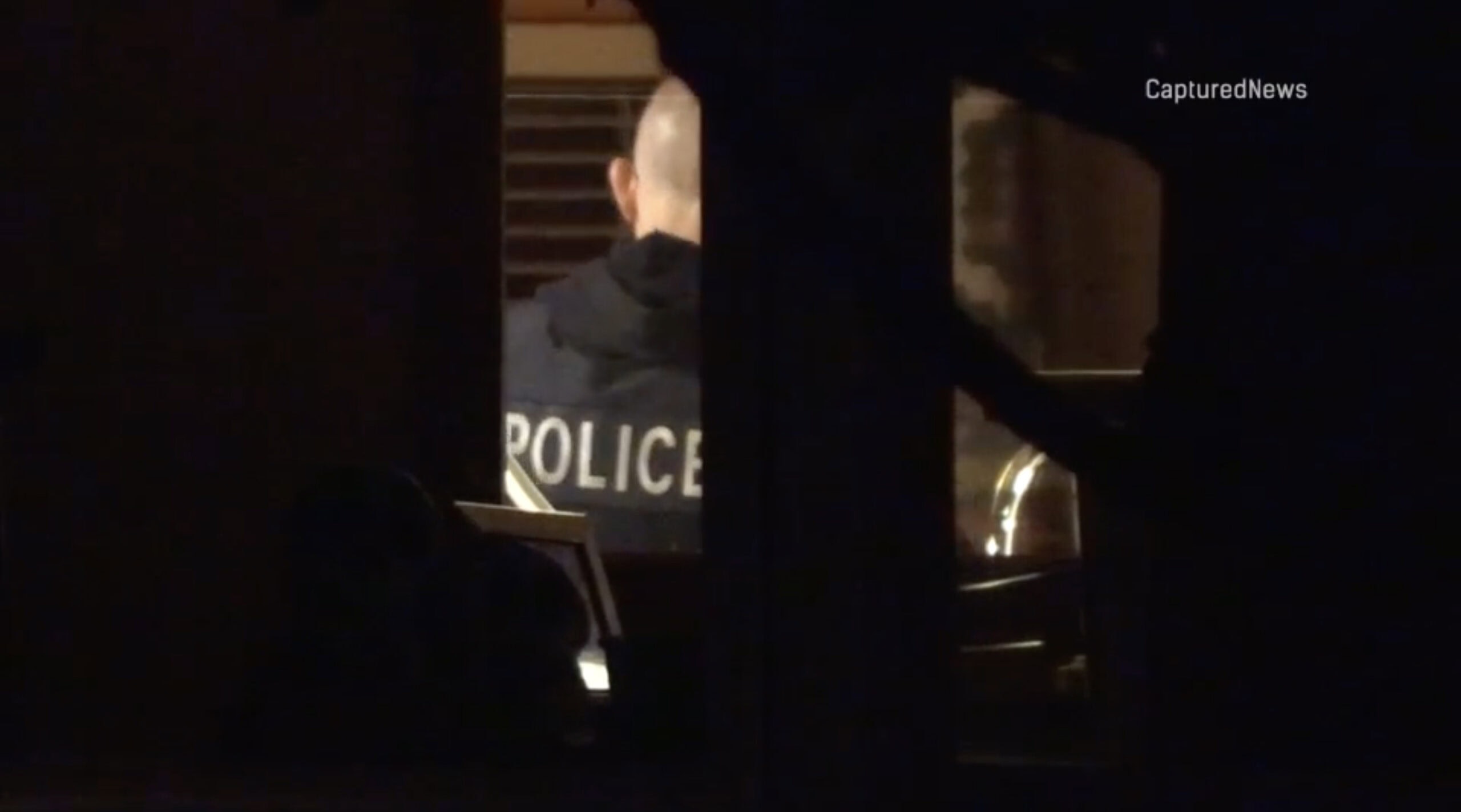 A police officer seen inside a darkened home at night