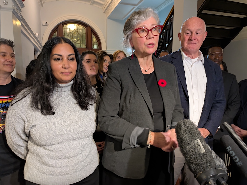 Three people &mdash; a young Indo-Canadian woman and a 60ish light-skinned woman and man &mdash; stand in a B.C. legislature hall.