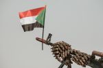 A Sudanese flag is held by a machine gun covered with an ammunition belt in Abraq, Sudan, on June 22, 2019.