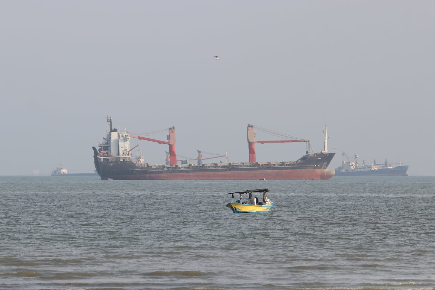 A boat floats as commercial vessels appear anchored in the Strait of Hormuz off Bandar Abbas, Iran, on Oct. 13.