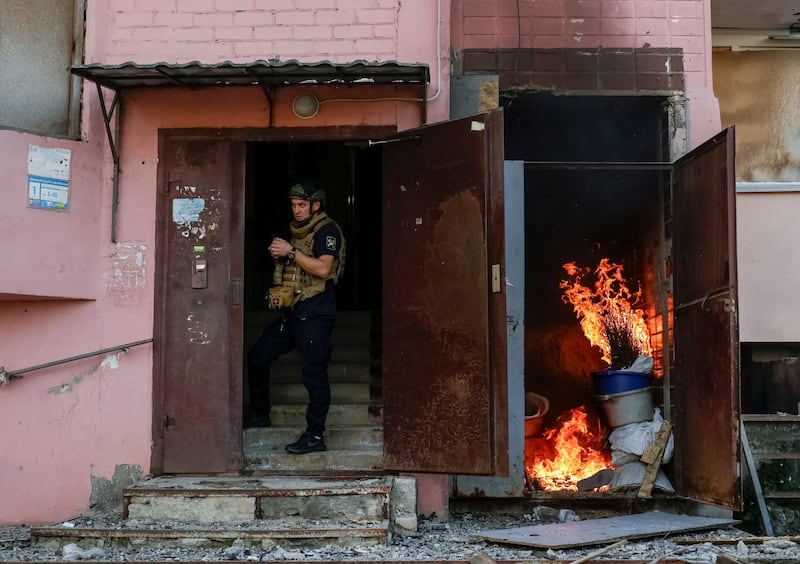 A rescuer takes shelter in an entrance of an apartment building amid the threat of another Russian drone strike, amid Russia's attack on Ukraine, in Kharkiv