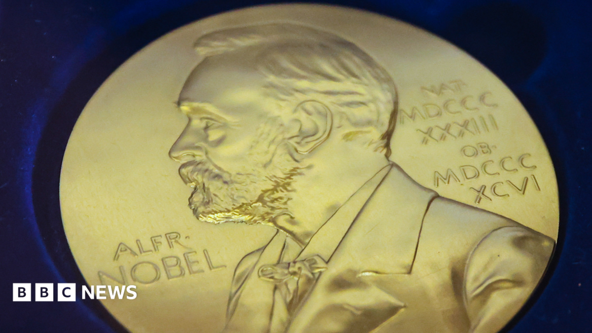 Gold medal in blue background with a picture of Nobel sketched out of the coin and roman numerals on the right.