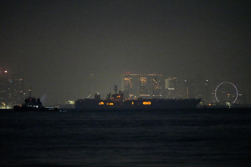 Aircraft carrier Abraham Lincoln seen in darkness sailing past Singapore.
