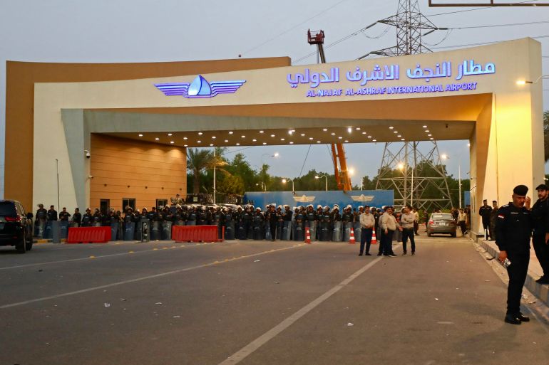 Security personnel stand guard as demonstrators gather outside the Al-Najaf Al-Ashraf International Airport in Najaf on September 28, 2026, demanding the facility to be reopened for flights from Iran.