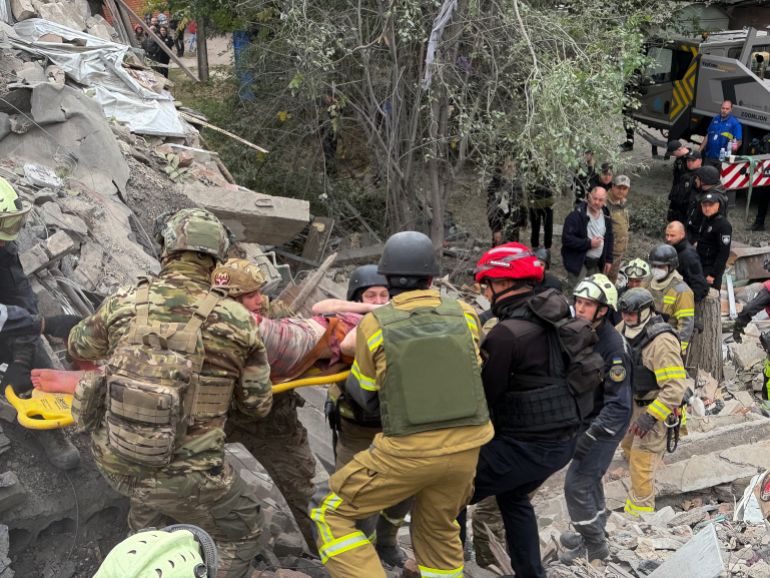 Rescuers evacuate a wounded woman on a stretcher from the rubble of a five-storey residential building damaged during a Russian attack which killed 16 people in Zaporizhzhia on October 10, 2026, amid the Russian invasion of Ukraine.