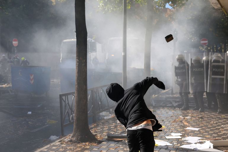 A protester throws a brick at police during clashes with riot police in central Tirana on October 14, 2026, as violence erupted for a second consecutive day during demonstrations demanding the resignation of Albanian Prime Minister and better education.