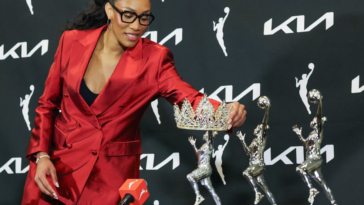 A'ja Wilson places a tiara over her 2026 WNBA MVP trophy at a news conference.