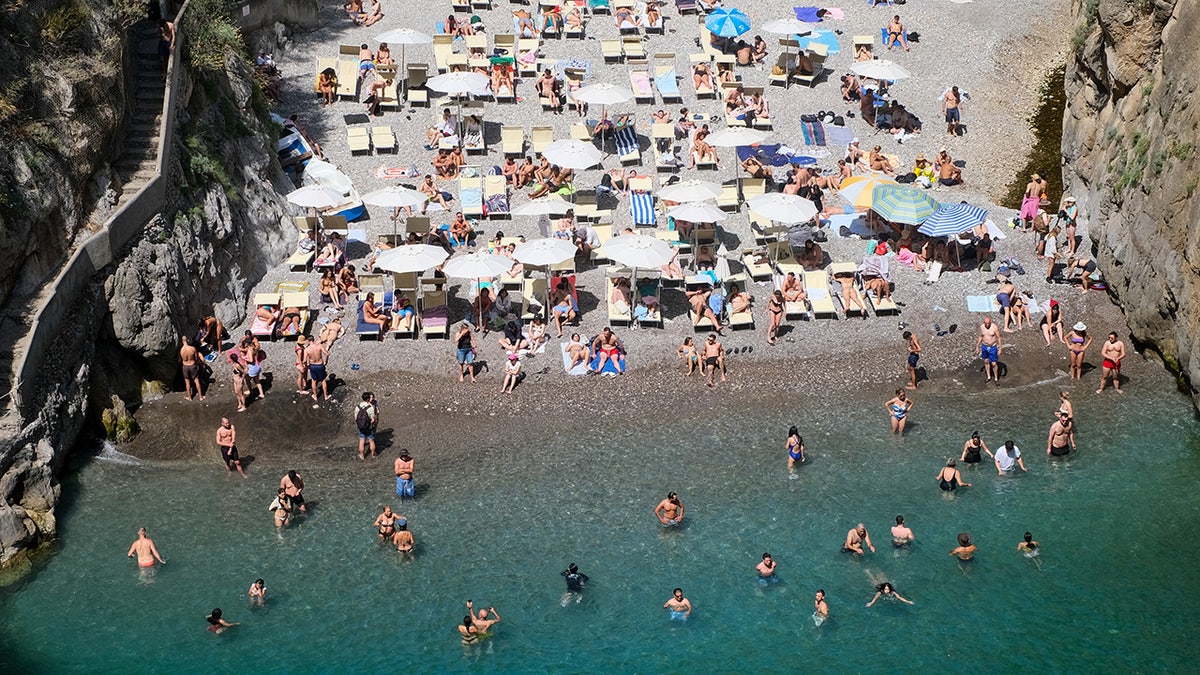 Tourists sunbathing in Fiordo di Furore beach in summer