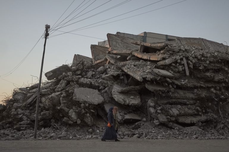 Two Palestinian women walk along a street lined with buildings destroyed during the Israel-Hamas war in Gaza City Wednesday, Oct. 14, 2026. (AP Photo/Jehad Alshrafi)