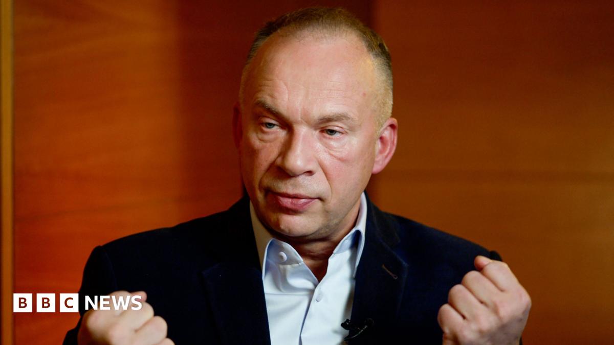 Oleksandr Syrskyi bunches his fists and sits in a dark blue jacket and light blue shirt