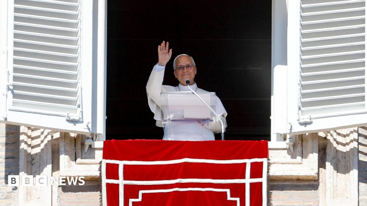 Pope Leo XIV delivering the Sunday Angelus prayer from the balcony of his residence overlooking St Peter's Square. He's in the traditional white cassock, mozzetta cape and zucchetto silk hat over his head.