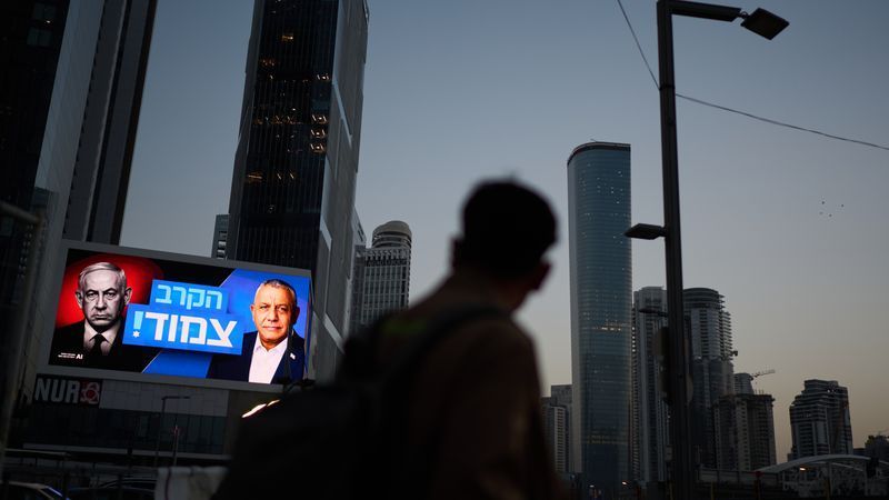 A pedestrian passes a campaign billboard featuring Israeli Prime Minister Benjamin Netanyahu, left, and his main rival, opposition candidate Gadi Eisenkot, with a message in Hebrew that reads "The race is tight," Friday, Oct. 23, 2026, in Tel Aviv, Israel. (AP Photo/David Goldman)