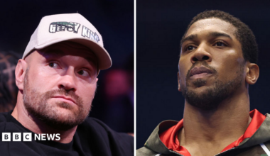 A composite image of Tyson Fury and Anthony Joshua. Tyson (left) wears a white boxing glove which is held in the air, and black shorts with the words 'Gypsy King' on. Joshua (right) is draped in a Union Jack flag and holds his fists up. He is wearing white boxing gloves.