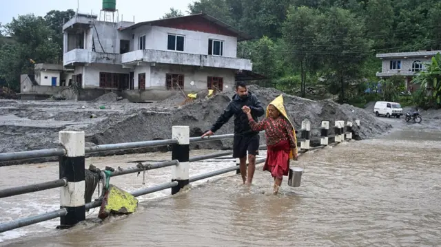 two people walk across a flooded bridge