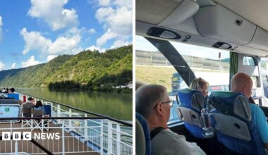 A photo taken out of a porthole on a river cruise vessel. Visible is the Dabune river with some trees in the background, against a blue sky.