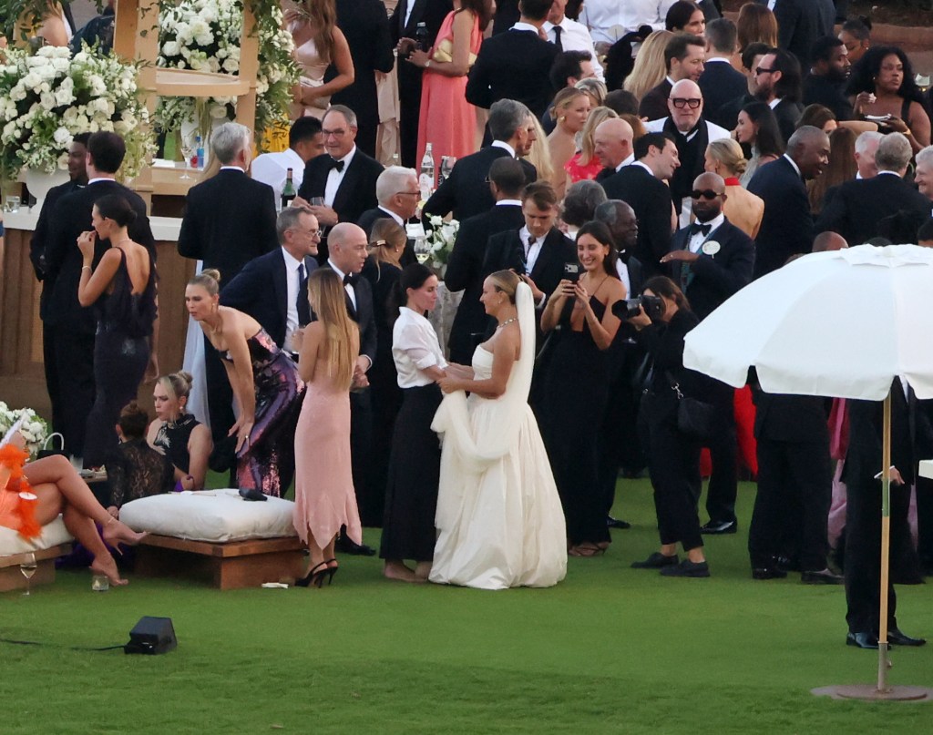 Jennifer Meyer in a wedding dress talking with Courteney Cox at her wedding reception, surrounded by guests in Hawaii.