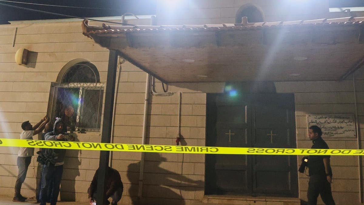 Journalists and other people stand outside a Greek Orthodox church in Jordan that was attacked.