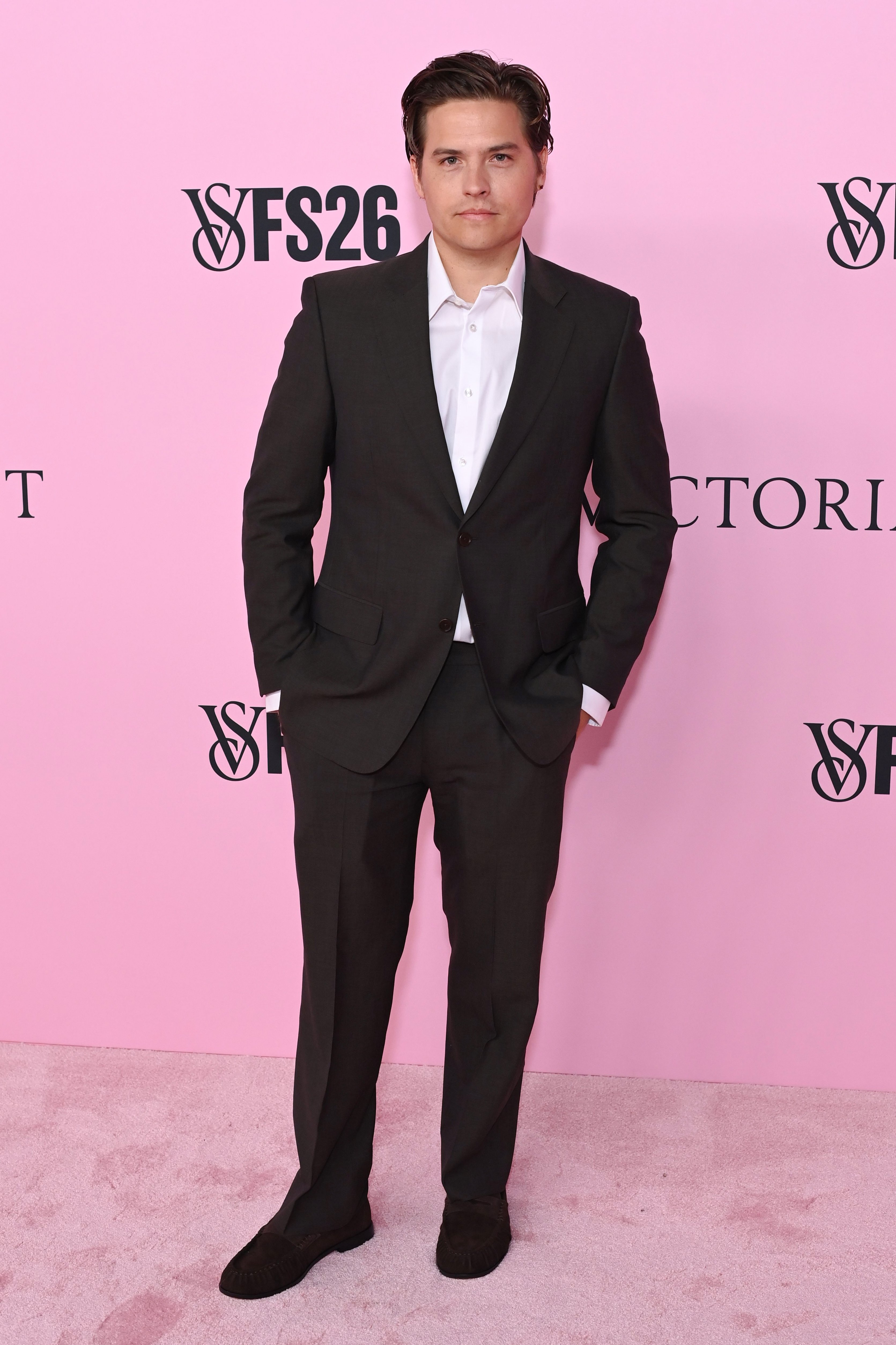 Cole Sprouse in a black suit on the pink carpet.