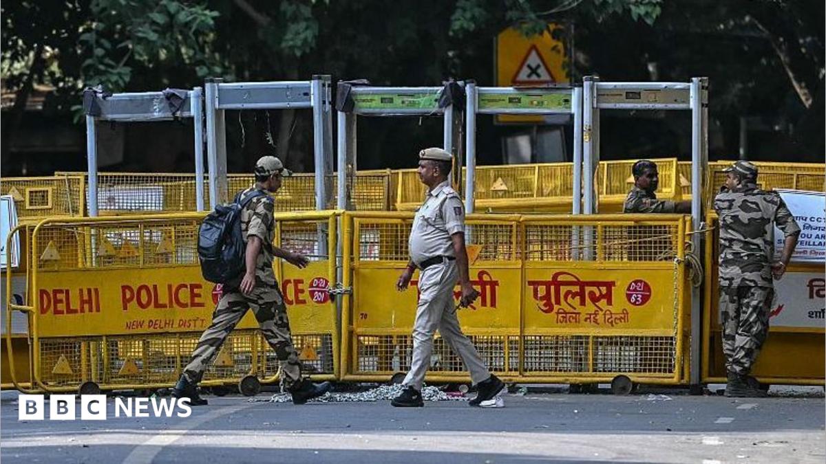 A protester holding a placard stands near the barricades in Delhi