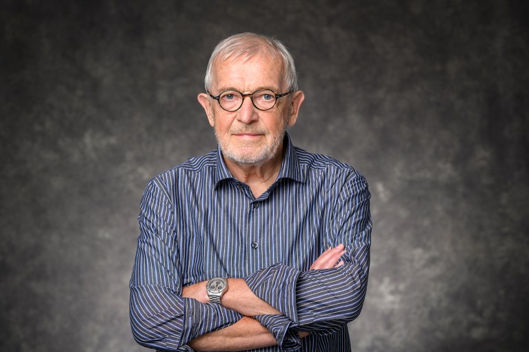 Portrait of Francis Halzen with his arms folded on a neutral grey background.