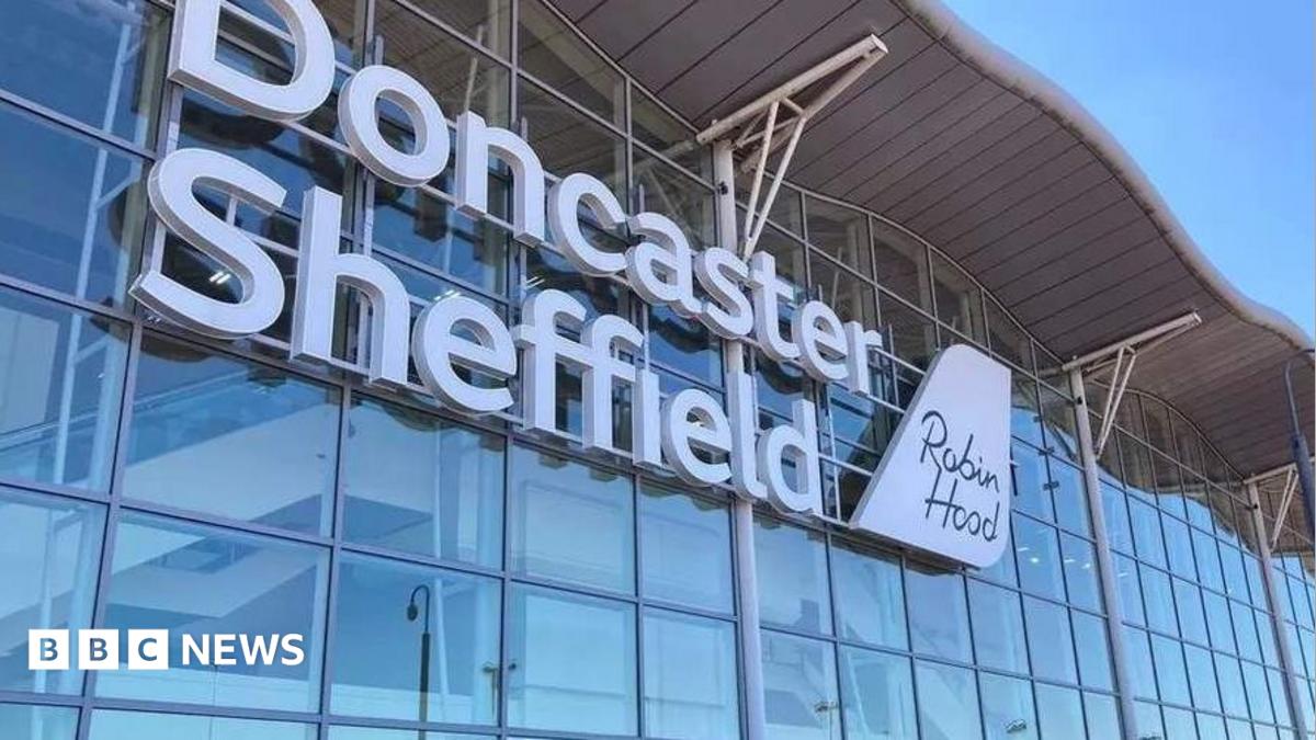 A wall made up of dozens of windows has large white lettering which says Doncaster Sheffield. There is a sign which looks like the tail of a plane saying Robin Hood.