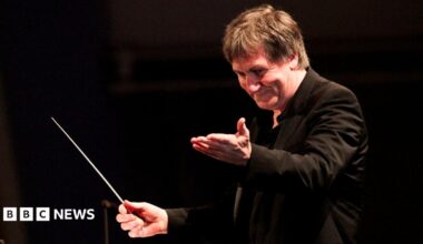 George Fenton conducts an orchestra, with a baton in his hand
