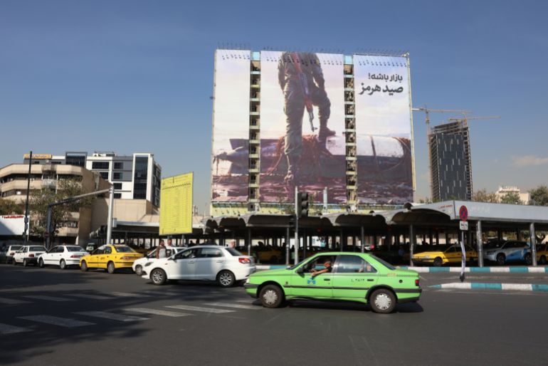 epa13302661 Iranians drive past an anti-US billboard depicting a member of Iran's Revolutionary Guard (IRGC) placing his foot on a US unmanned underwater vehicle that Iran claims to have seized in the Strait of Hormuz, with the Persian words 'Hormuz Catch', in Vanak Square in Tehran, Iran, 14 October 2026, amid the ongoing conflict between Iran and the United States. EPA/ABEDIN TAHERKENAREH RESTRICTIONS: NO Access Israel Media/Persian Language TV Stations Outside Iran/Strictly No Access BBC Persian/VOA Persian/Manoto TV/Iran International TV. (As mandated by Iran's Directorate General for Foreign Media) --