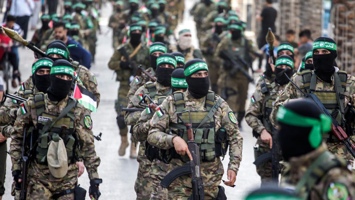 Members of the Ezz-Aldine Al-Qassam Brigades march with guns in a street in Gaza.