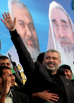 A grey-haired man waves to supporters as he arrives to speak at a rally.