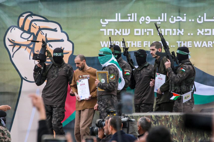 Hamas fighters escort Israeli hostages Or Levy, second right, and Eli Sharabi, second left, off a stage before handing them over to a Red Cross team in central Gaza on February 8, 2025.