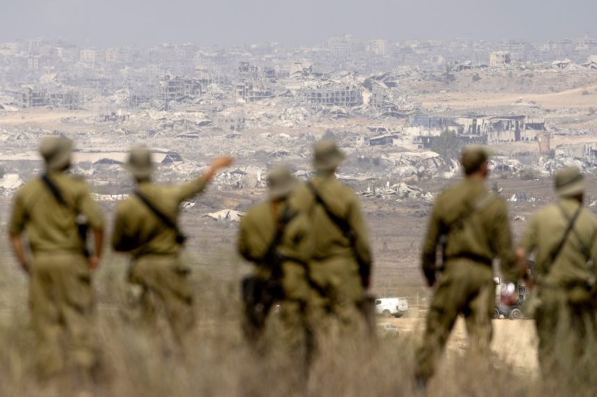 Israeli soldiers look across to northern Gaza from a viewpoint on the Israeli side of the border on August 13, 2025.