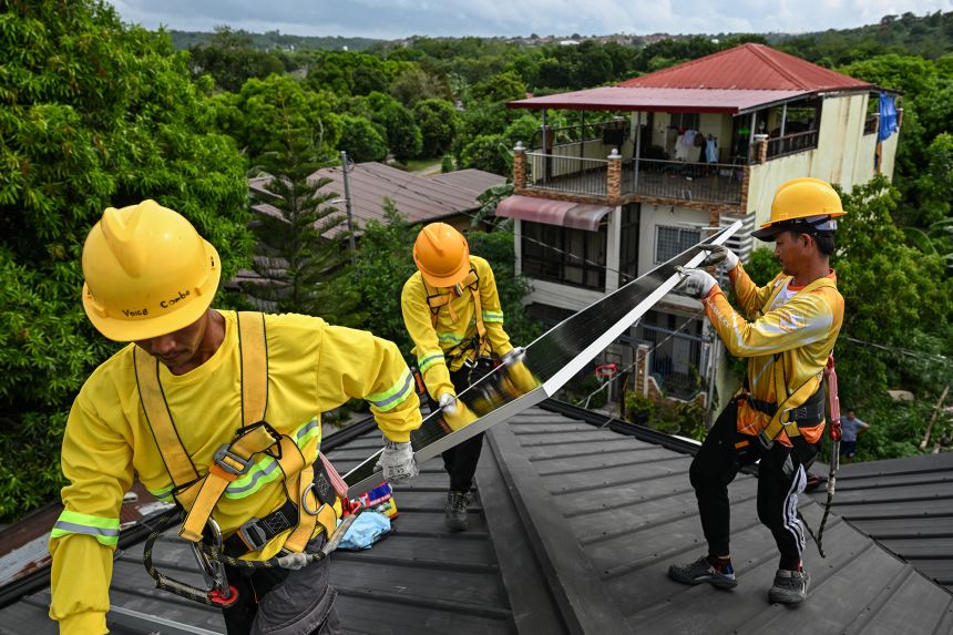 Workers install solar panels on a roof in Carmona, in the Philippine province of Cavite, on July 9.