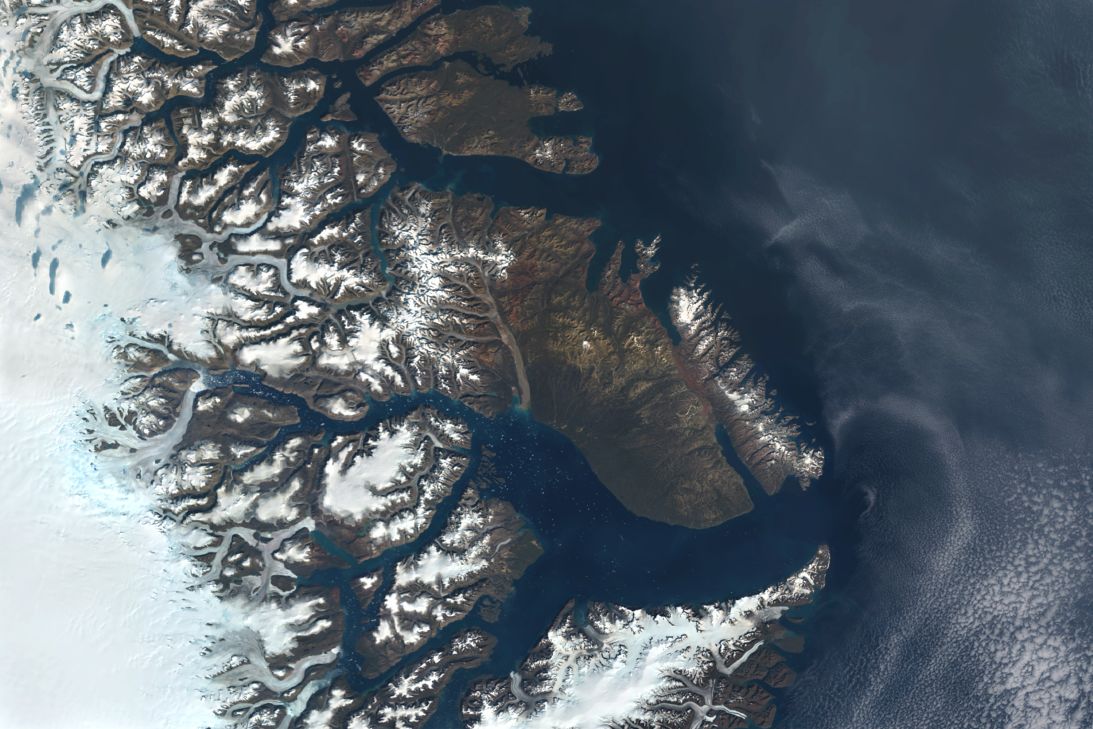 Satellite view of the Jameson Land Basin in East Greenland, near Scoresby Bay and the settlement of Ittoqqortoormiit, serviced by Nerlerit Inaat Airport. The basin is regarded as a potential multibillion‑barrel oil and gas reserve, drawing investor interest for its untapped energy resources.