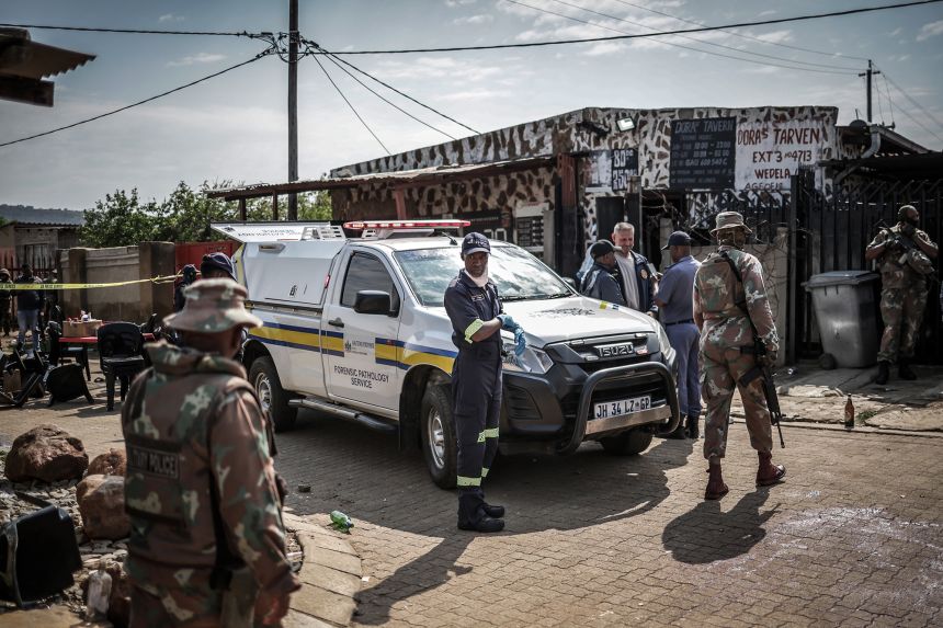 Members of South Africa's Forensic Pathology Service and South African National Defence Force (SANDF) inspect and secure the scene where gunmen armed with assault rifles stormed a bar in Johannesburg on September 27.