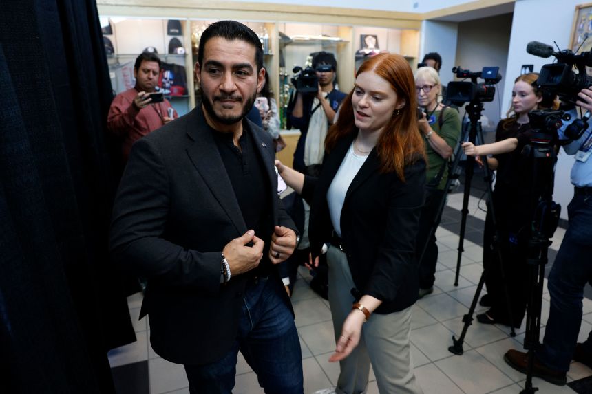 Abdul El-Sayed is escorted out by his spokesperson Roxie Richner, after speaking to the media at the Council of Carpenters & Millwrights facility in Warren, Michigan on October 3.