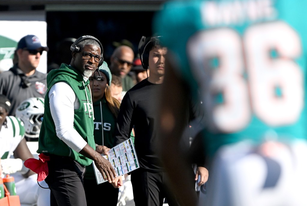 New York Jets head coach Aaron Glenn stands on the sideline holding a play sheet during a game.