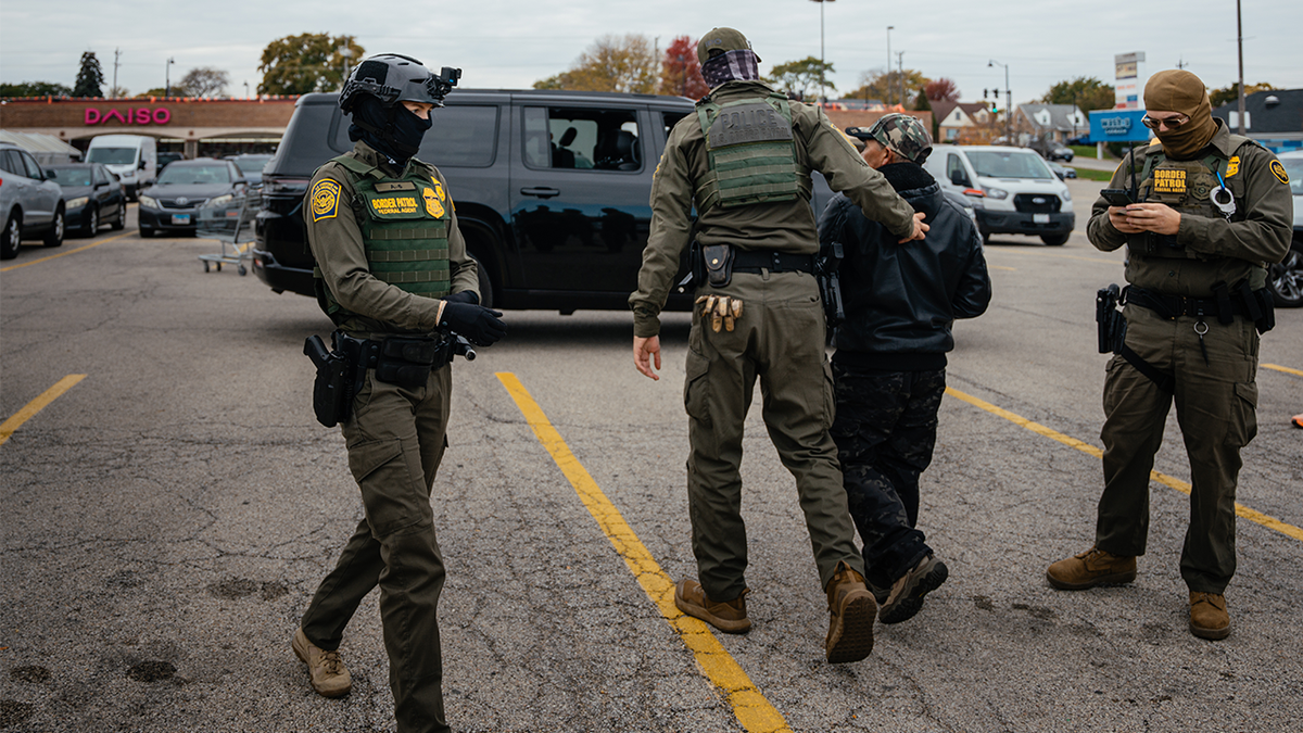 Federal immigration agents arrest a man in the parking lot of an H-Mart grocery store on October 31, 2025, in Niles, Illinois.