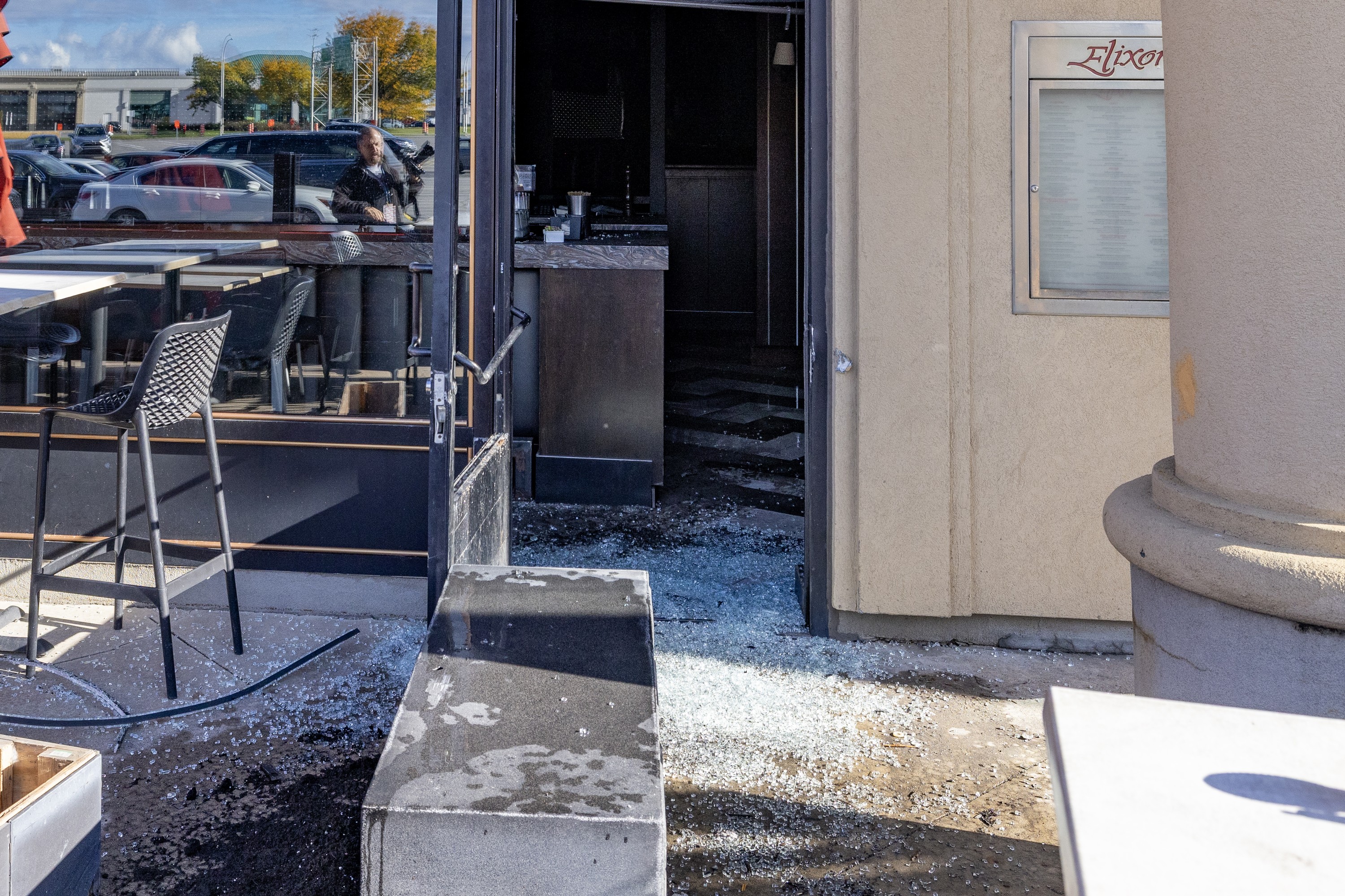 The front of a restaurant with debris from a broken window and firebombing.