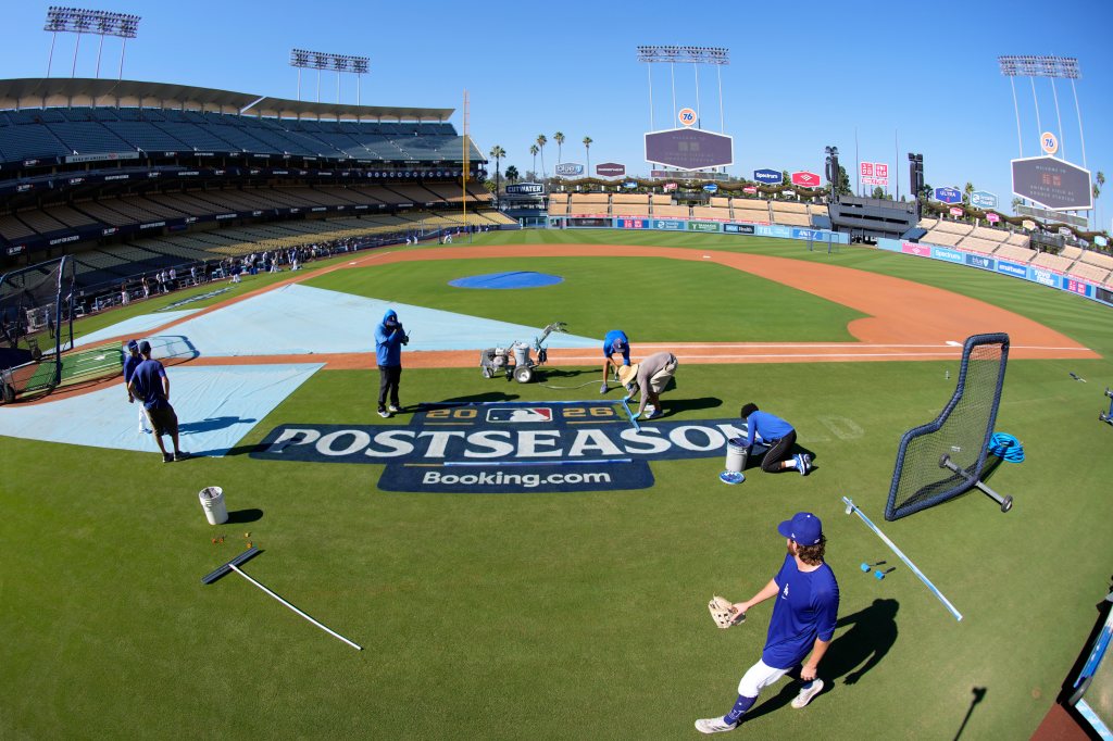 Members of the Los Angeles Dodgers grounds crew paint a postseason logo on the field prior to practice.