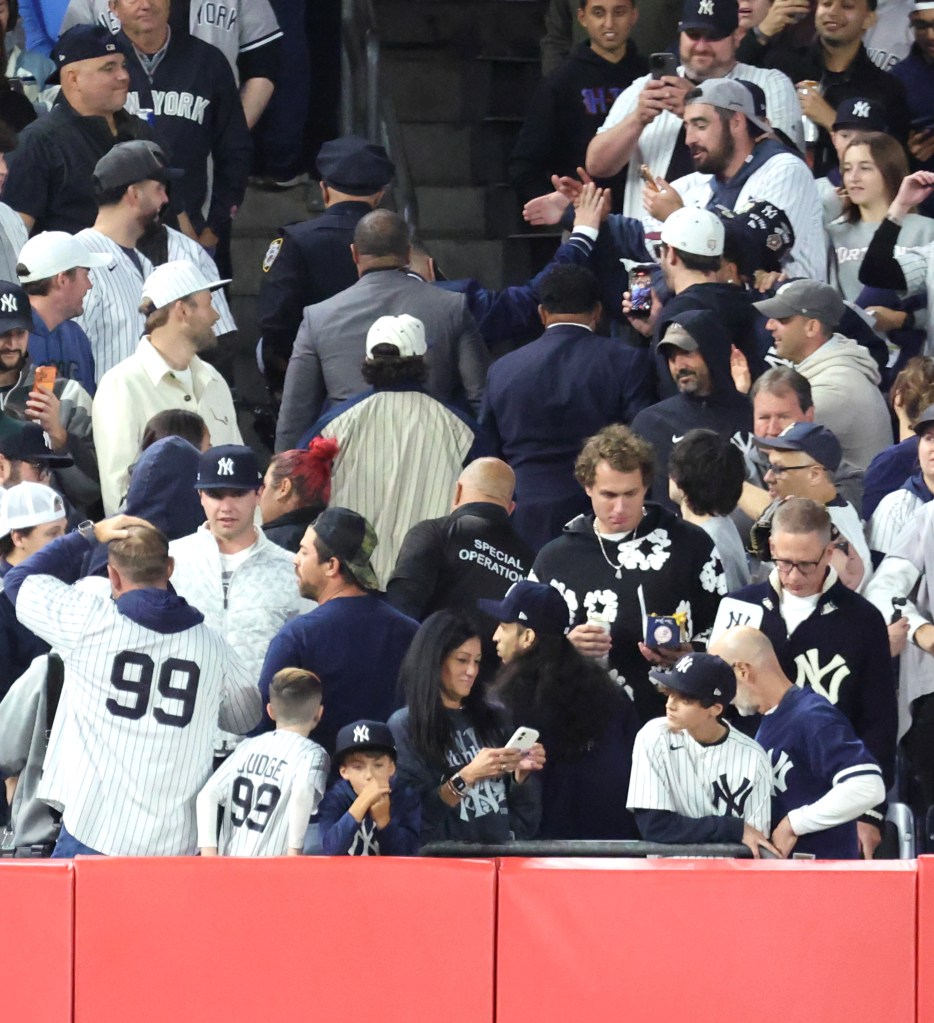 A fan who interfered with a ball hit by New York Yankees shortstop Anthony Volpe is escorted out of the stands at Yankee Stadium during the American League Division Series.