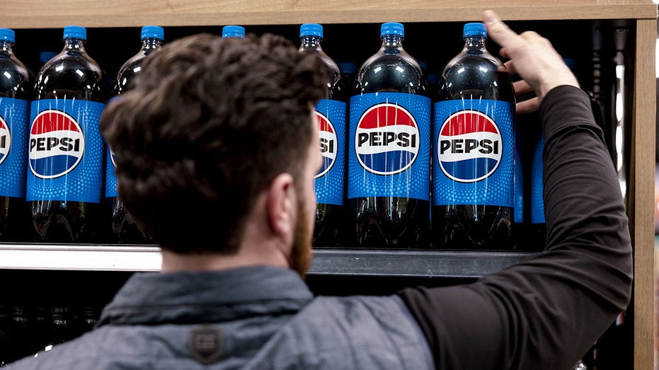 A worker puts Pepsi bottles on a shelf.