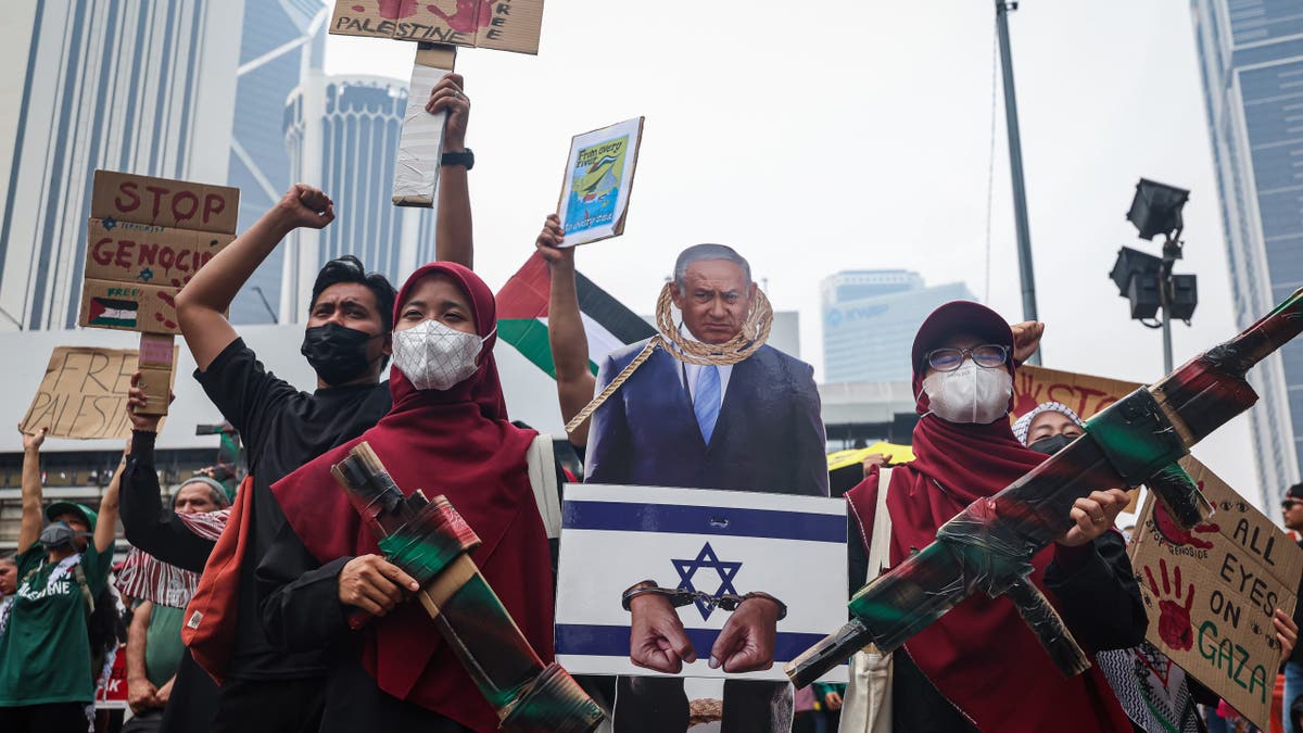 Anti-Israel demonstrators carry a cutout of Benjamin Netanyahu and placards during a rally in Kuala Lumpur.